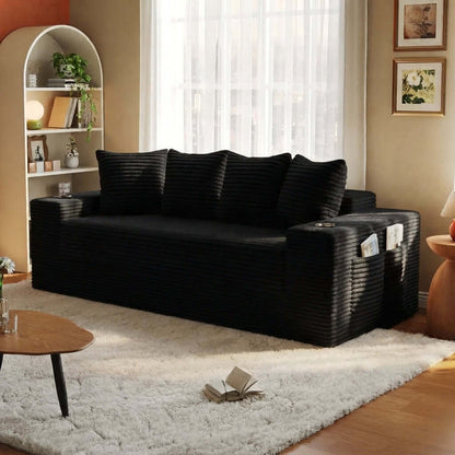 Convertible Sofa Bed-Modern Foldable Sofa For Small Spaces in cozy living room setting, featuring modular design and 50D high-density sponge. A black corduroy sofa slipcover fitted over a three-seater sofa in a warm, styled living room with a white shag rug, wooden floor, and shelving.